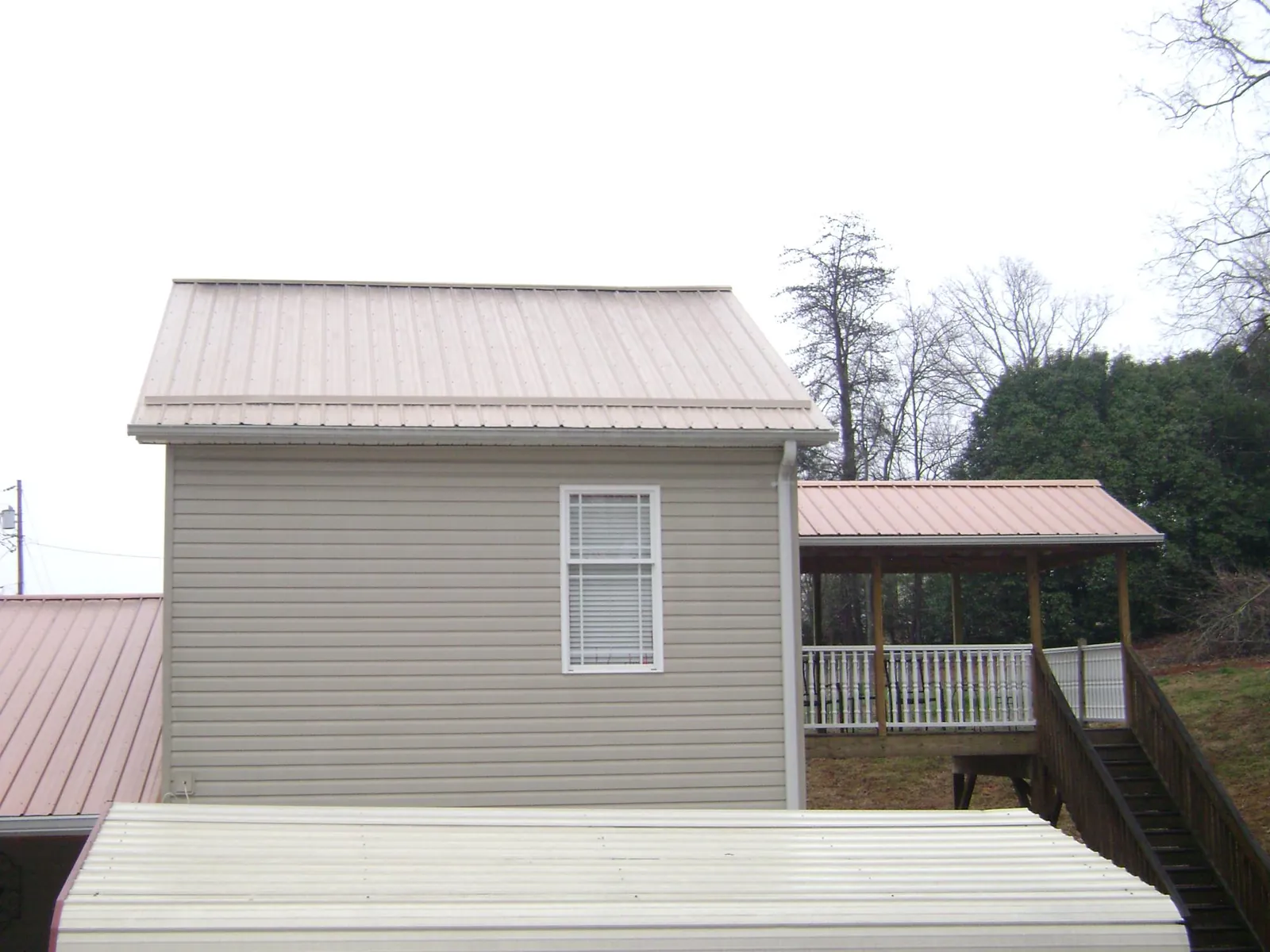 Tan metal roofs on a two story addition and attached porch, from a Roof Replacement job in Rockland